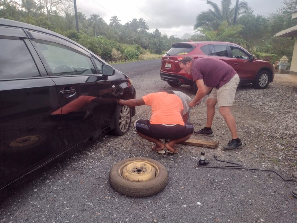 Chief Jared, Scott and Uncle Bob are removing the flat tire from the rental car on the side of the beach road